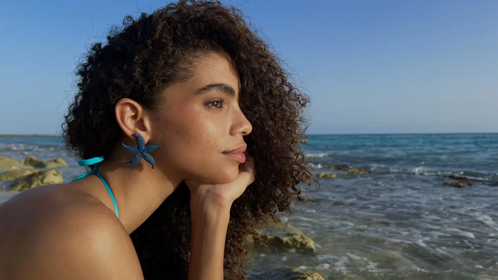 Mujer con aretes turquesa Meycho frente al mar