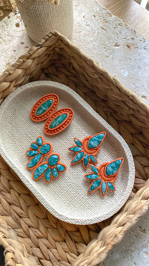 Aretes Meycho naranja y turquesa en una bandeja tejida